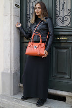 Charger l'image dans la galerie, Sac Berthille Mini Cortina orange, tannage végétal, extérieur en cuir grainé plaine fleur, porté par notre mannequin.