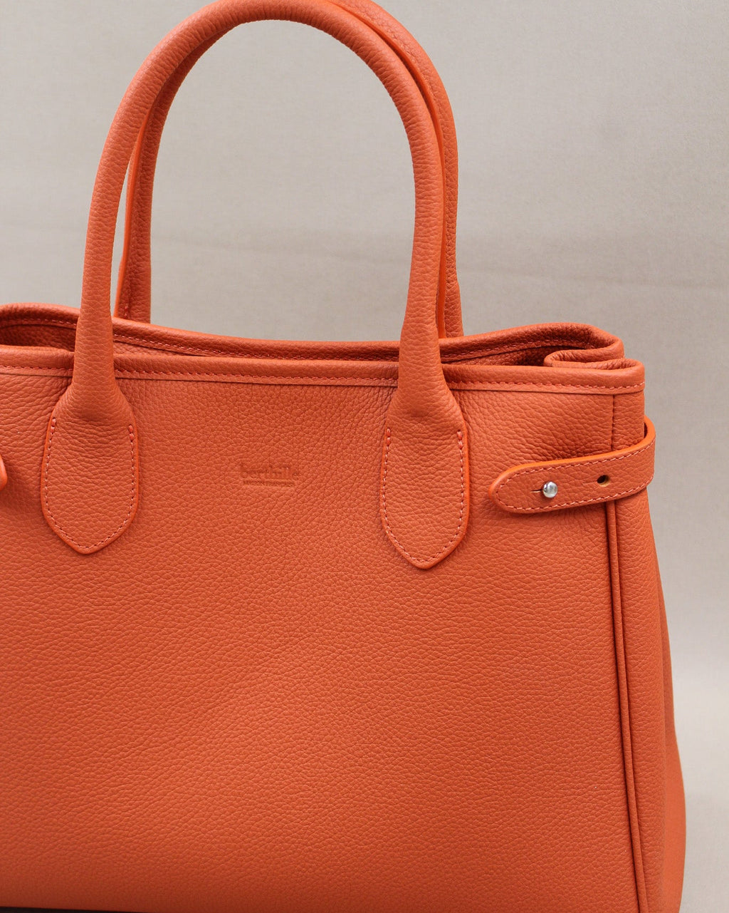 Gros plan anses et logo gravé, sac Saint-Moritz cuir grainé orange butano Berthille
