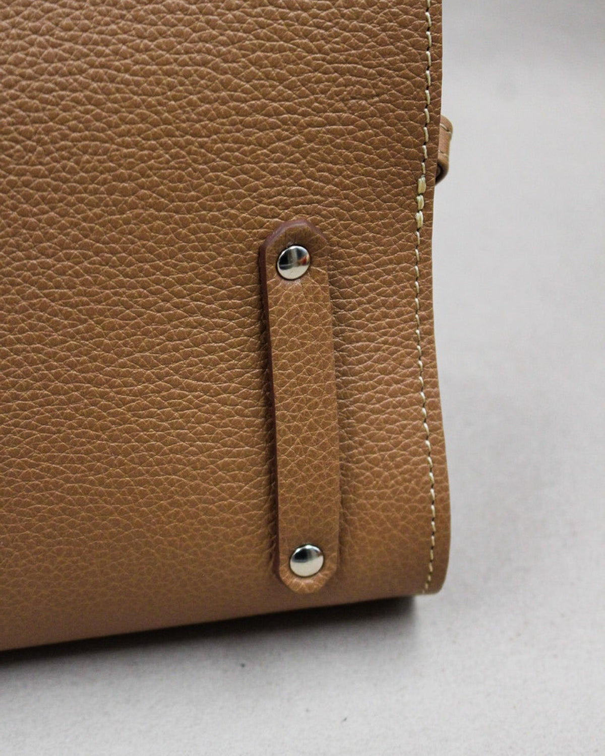 Gros plan attache boutonnée sur sac cuir grainé camel Berthille