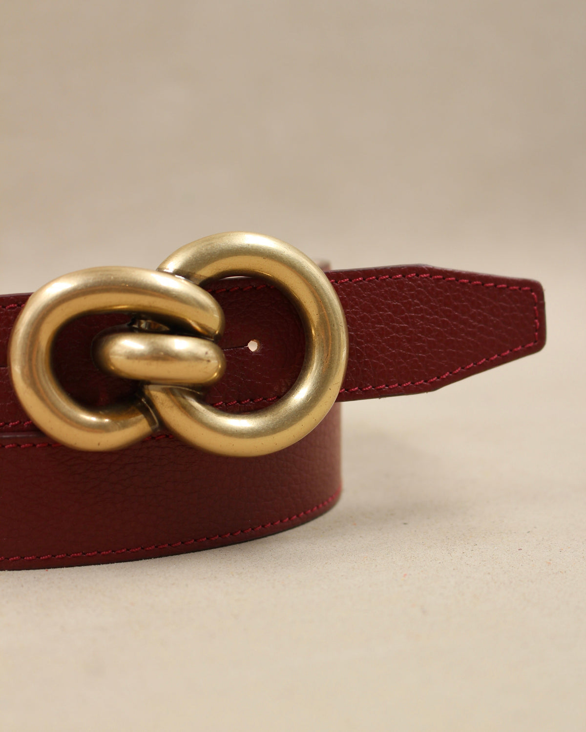 Gros plan boucle double anneaux dorée sur ceinture cuir grainé bordeaux Berthille