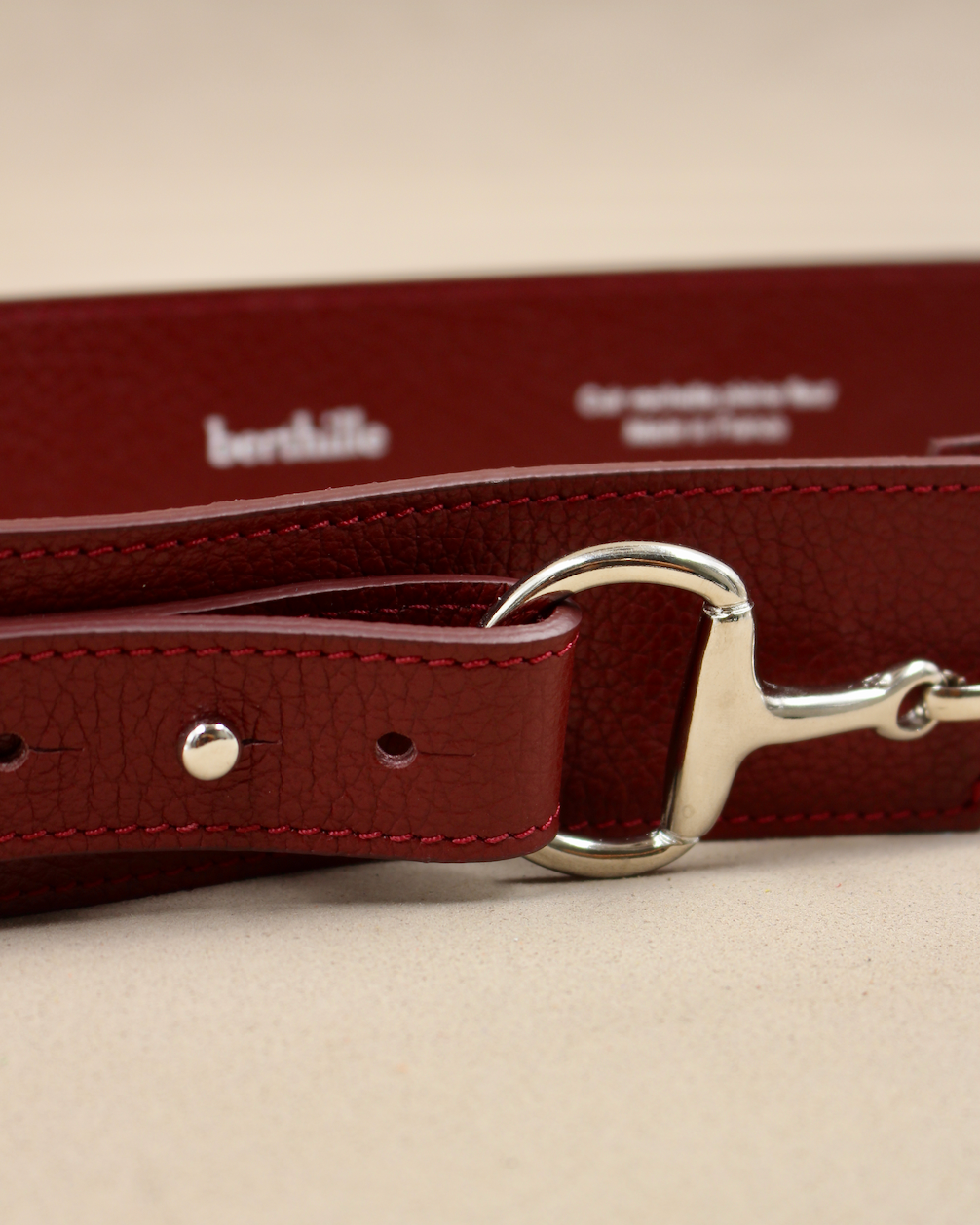 Gros plan boucle mors de cheval argentée sur ceinture cuir vachette bordeaux Berthille