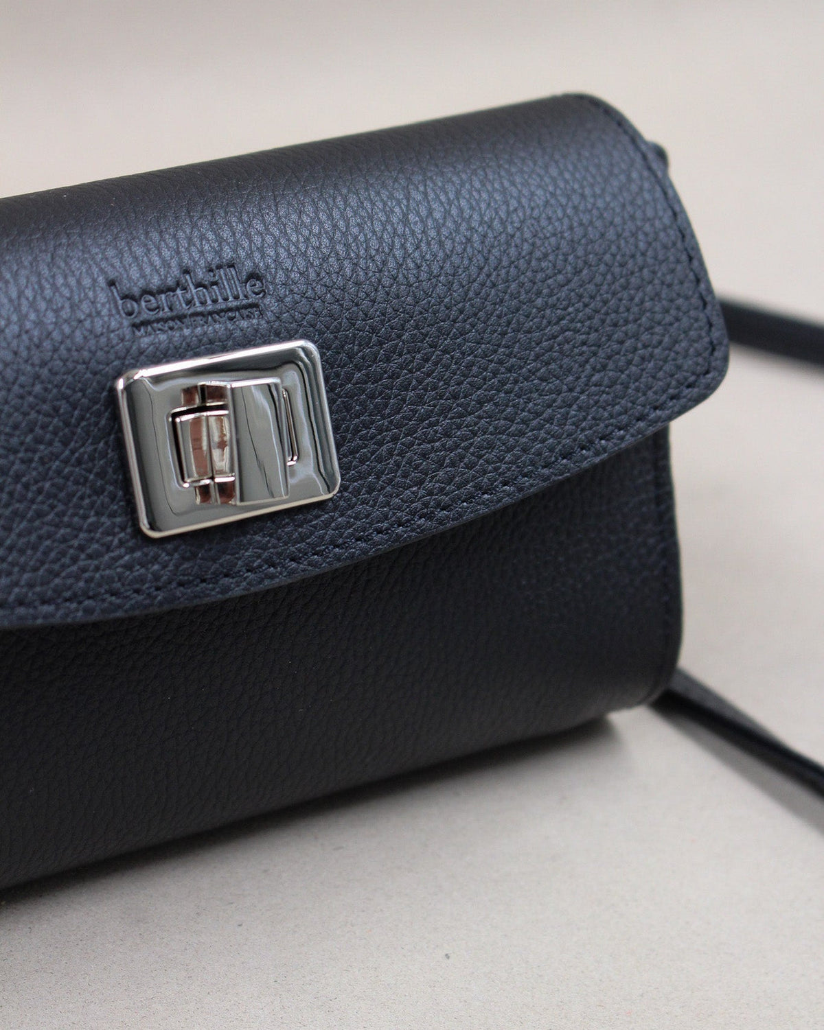 Gros plan fermoir tourniquet argenté sur sac cuir grainé bleu marine Berthille