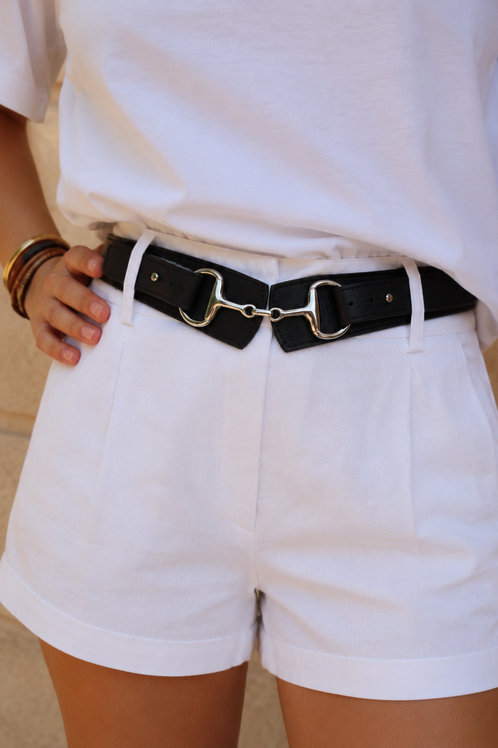 ceinture noir en cuir avec une boucle morte de cheval porter par une femme habiller tout en blanc 