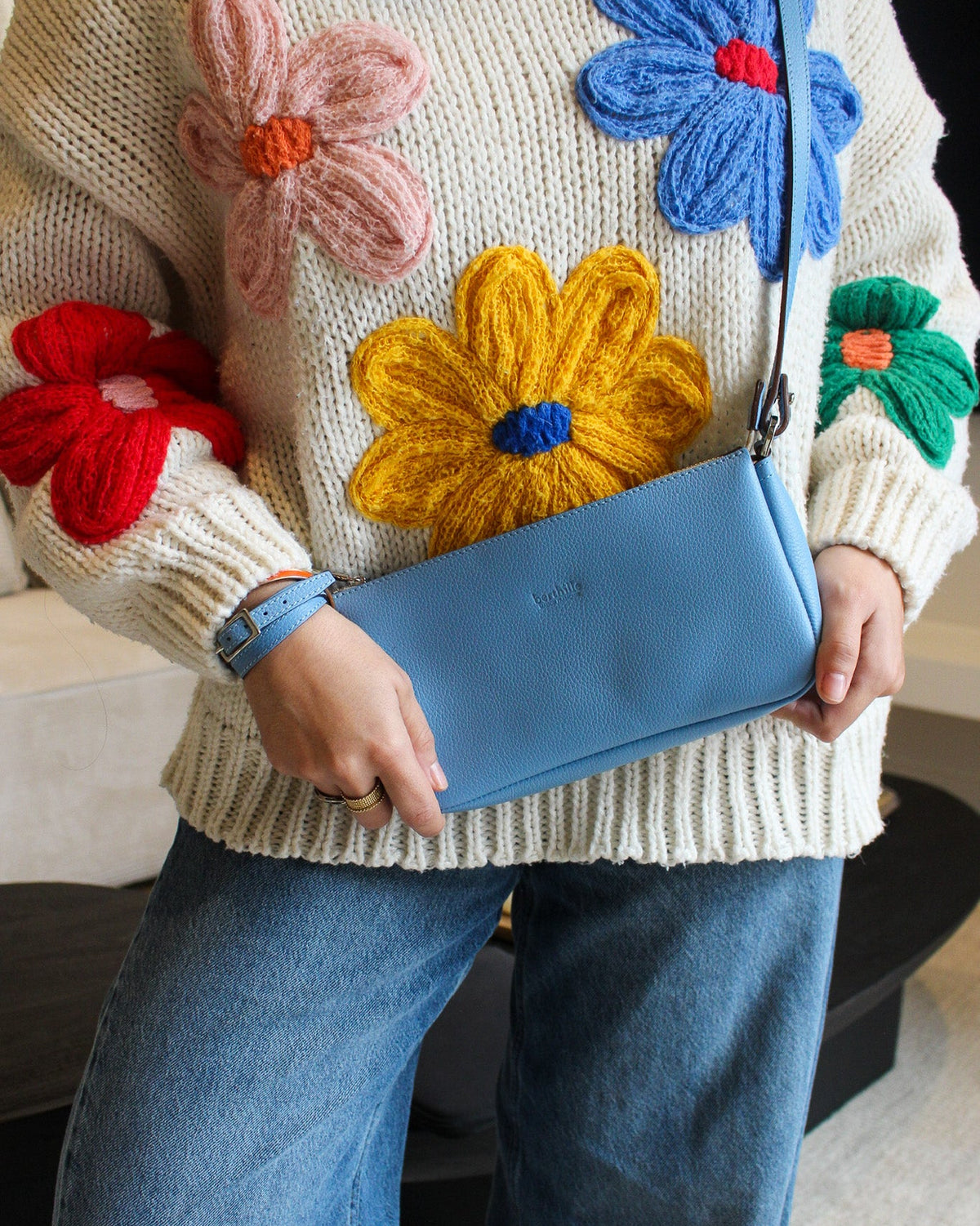 Pochette Berthe cuir bleu ciel portée à la main, bandoulière fine Berthille