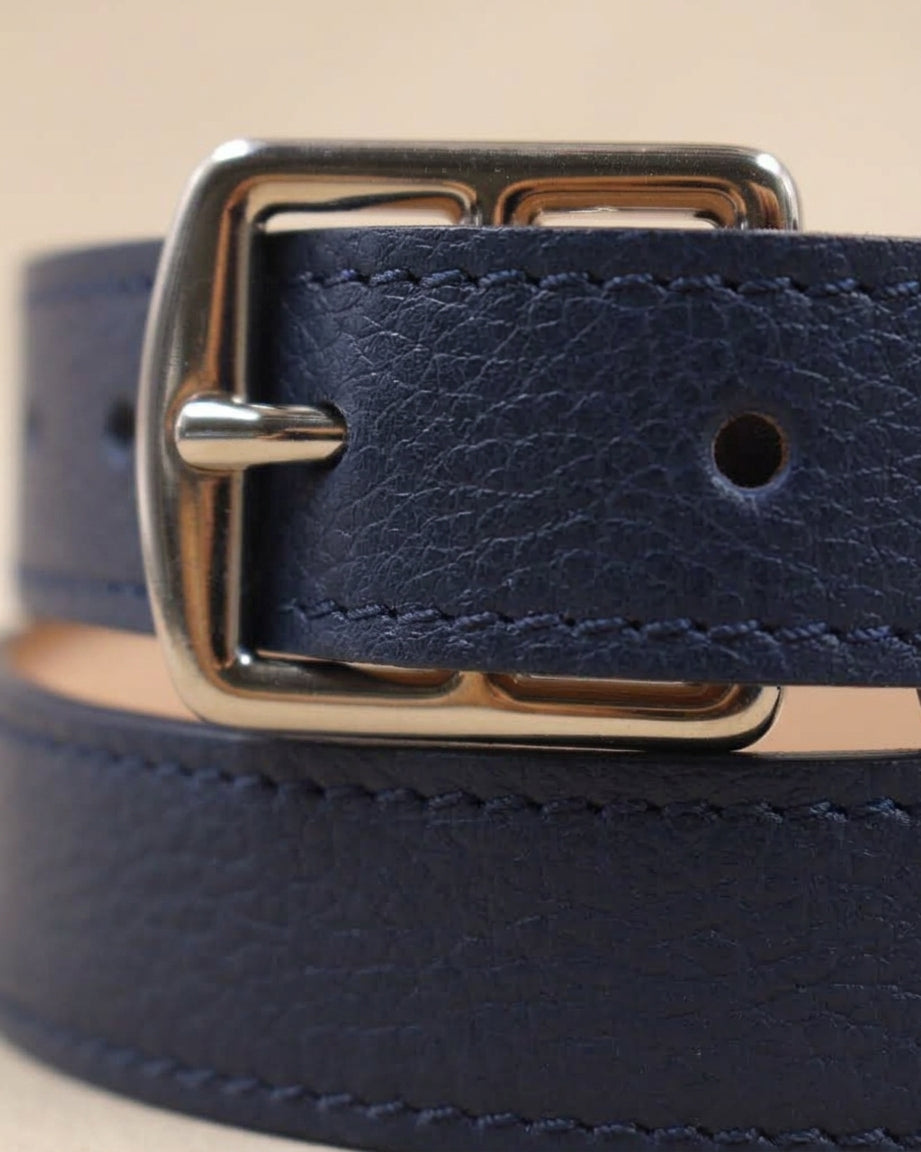 Gros plan sur la boucle argentée et le cuir grainé bleu marine de la ceinture étrivière fine Berthille, surpiqûres visibles
