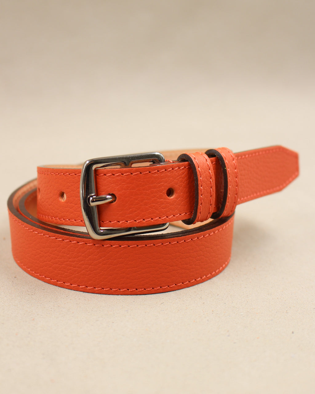 Ceinture étrivière fine Berthille en cuir grainé orange enroulée, boucle argentée et bout pointu
