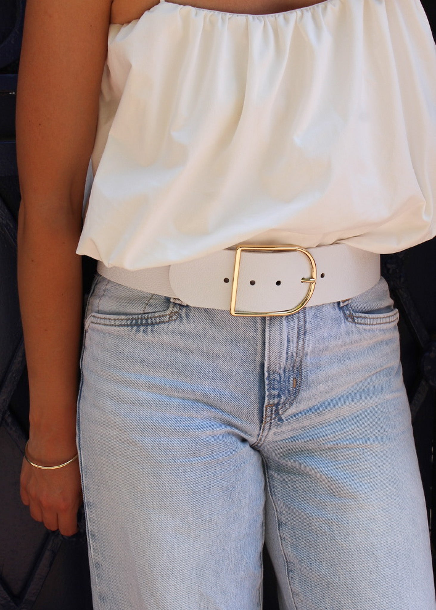 Ceinture berthille demi lune en cuir couleur blanche porter par une femme avec un top blanc et un jean 