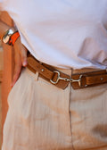 ceinture couleur marron clair avec un fermoir morse de cheval sur une femme avec un pantalon beige et un tee-shirt blanc