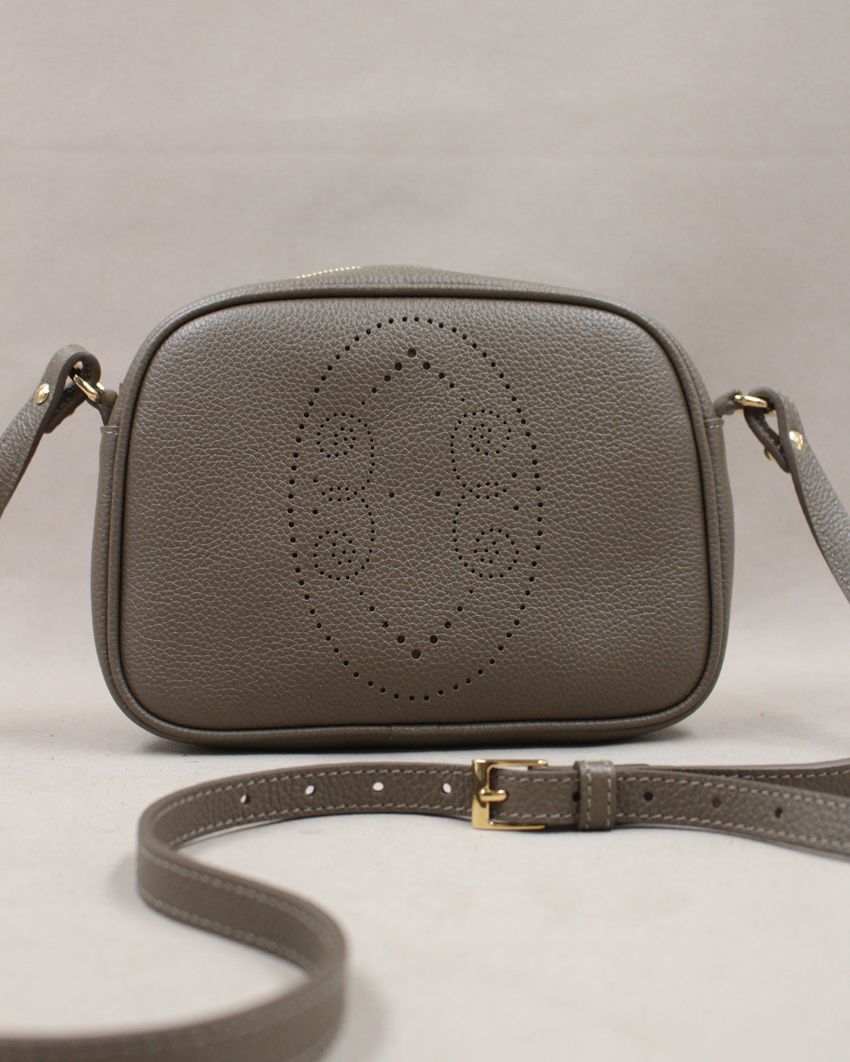 Pochette Trianon en cuir taupe vue de face, motif perforé bout fleuri et bandoulière réglable, fabriquée en France par Berthille