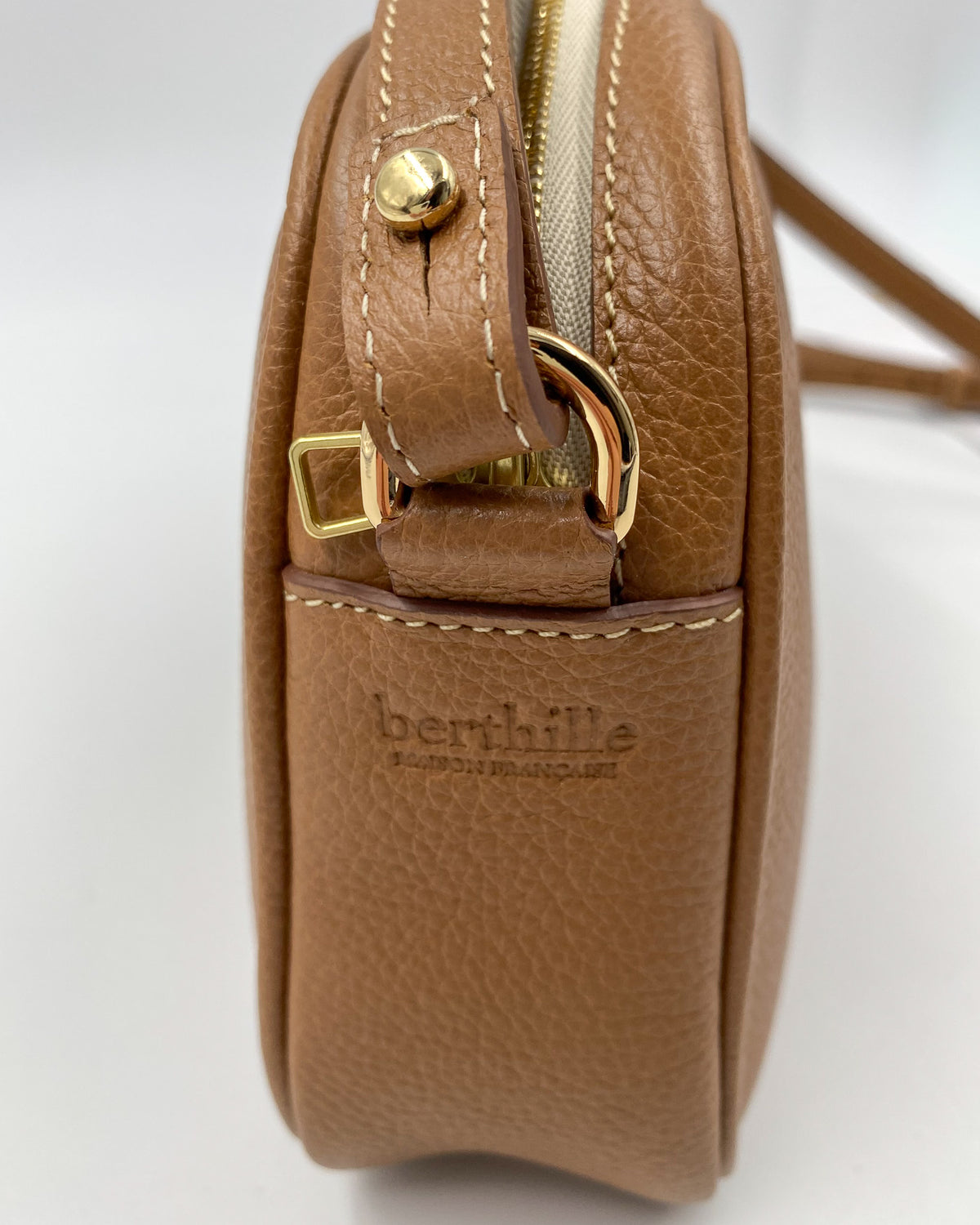 Dos de la pochette Trianon en cuir camel grainé, poche plaquée et logo Berthille Maison Française embossé