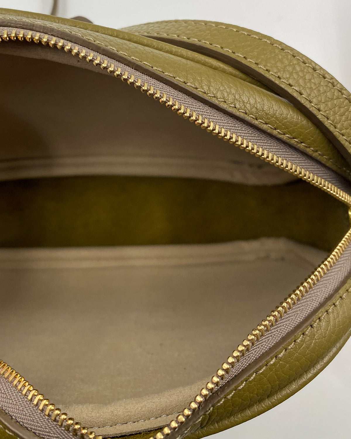 Intérieur de la pochette Trianon en cuir kaki : doublure beige, deux compartiments et fermeture éclair dorée