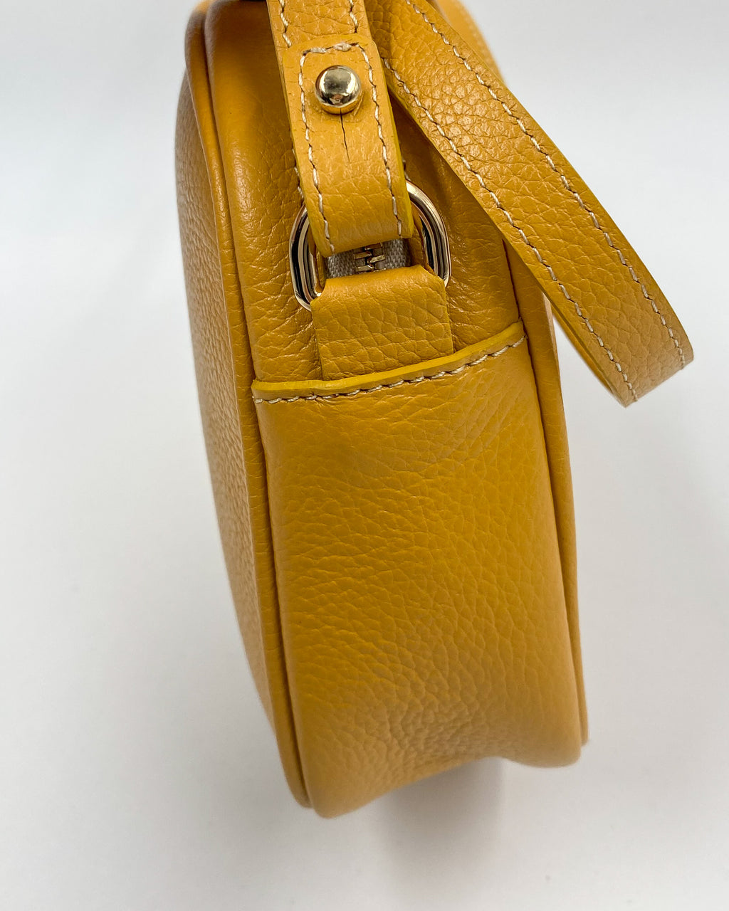 Vue de côté de la pochette Trianon en cuir jaune moutarde grainé, attache de bandoulière dorée et coutures sellier, fabrication artisanale française