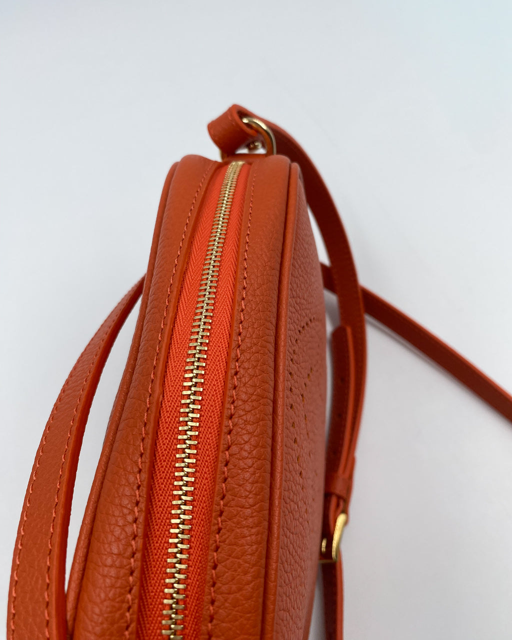 Vue du dessus de la pochette Trianon en cuir orange grainé, fermeture éclair dorée et coutures ton sur ton, fabrication artisanale française