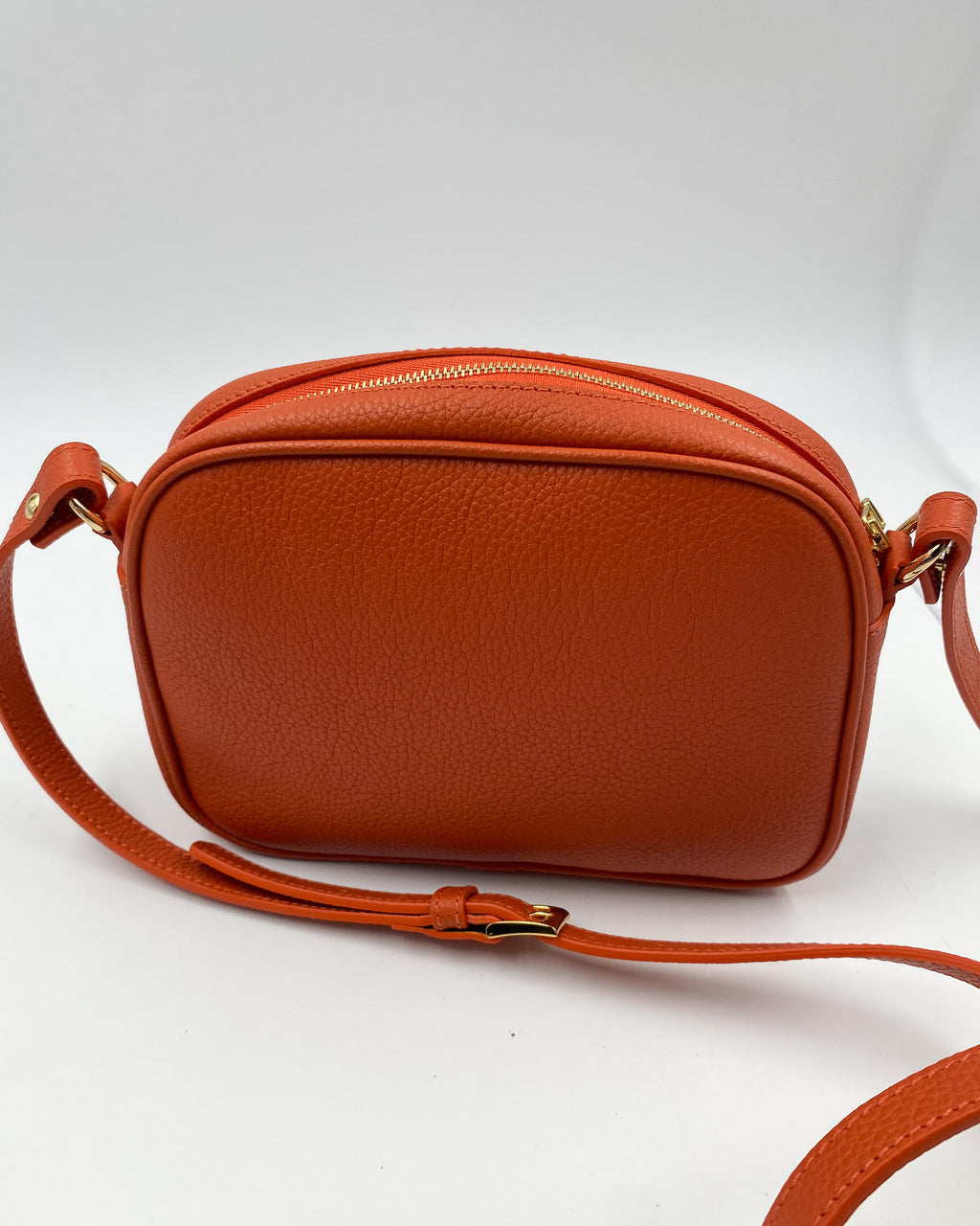 Dos de la pochette Trianon en cuir orange grainé, fermeture éclair dorée et bandoulière réglable, maroquinerie artisanale Berthille