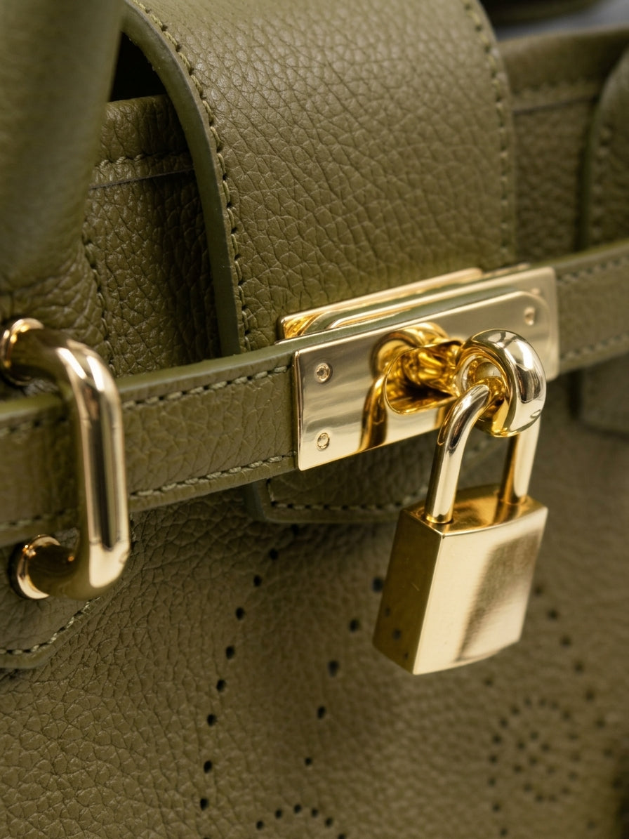 Détail du sac à main Mini Vendôme en cuir kaki grainé : sangle ceinturée, fermoir et cadenas dorés, motif perforé bout fleuri, savoir-faire artisanal français