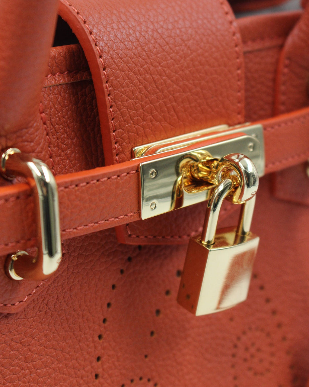 Détail du sac à main Mini Vendôme en cuir orange grainé : sangle ceinturée, fermoir et cadenas dorés, motif perforé bout fleuri, savoir-faire artisanal français