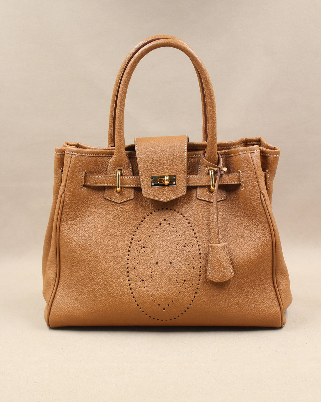 Sac à main Vendôme en cuir camel vue de face, motif perforé bout fleuri, deux anses, sangle ceinturée, fermoir tournant doré et clochette en cuir, fabriqué en France par Berthille