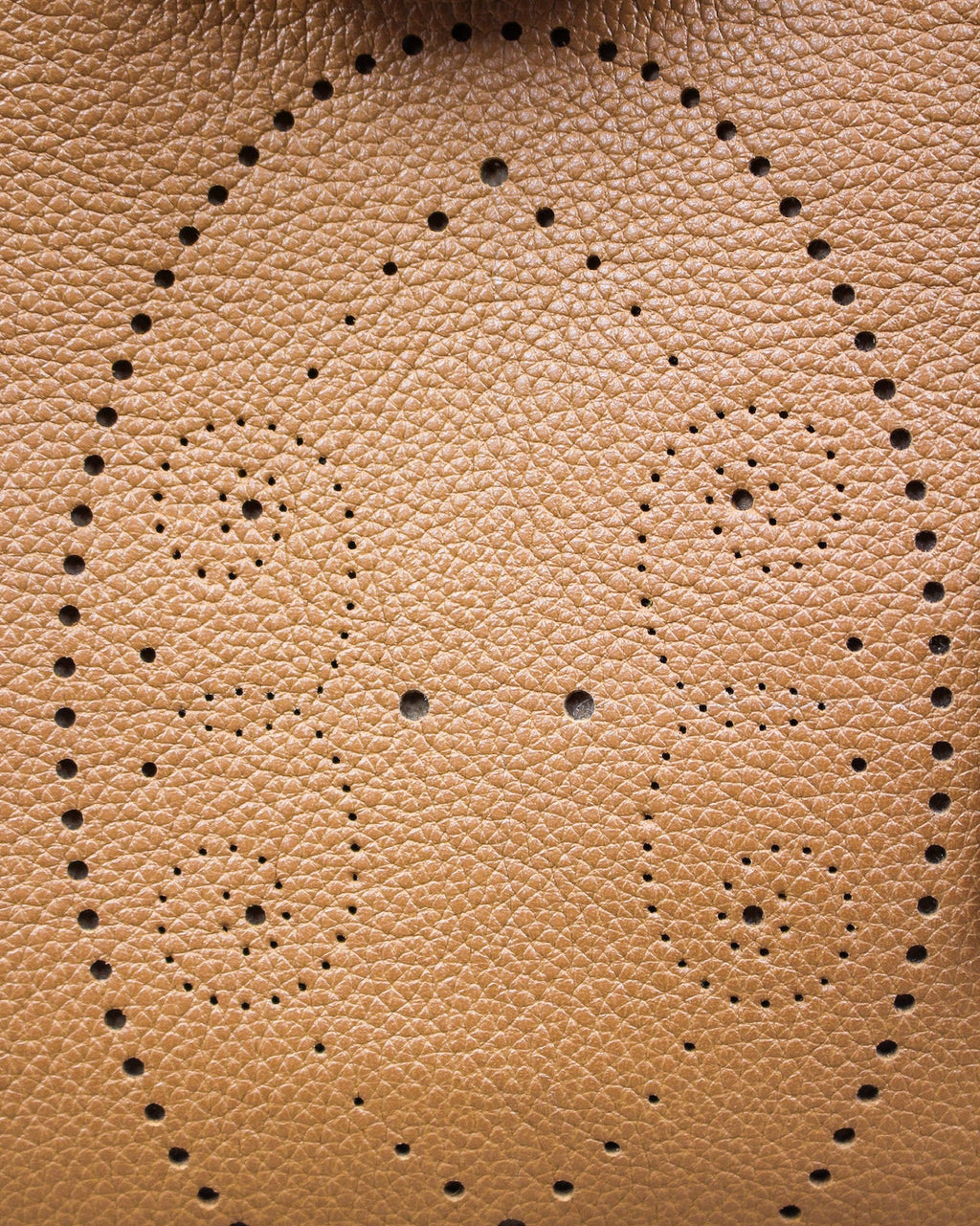 Gros plan sur le motif perforé bout fleuri réalisé à la main sur le cuir camel grainé du sac Vendôme, savoir-faire artisanal Berthille