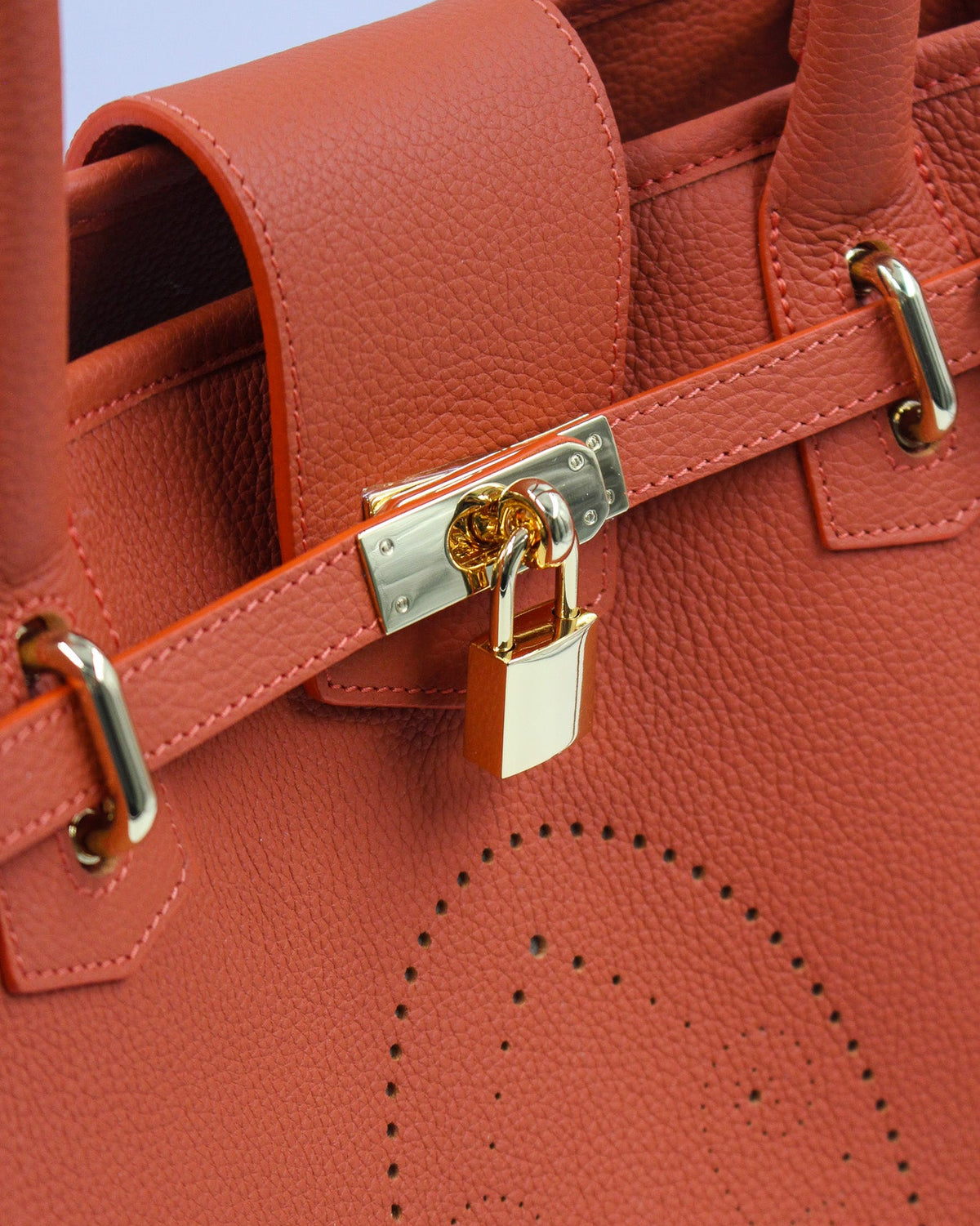 Détail du sac à main Vendôme en cuir orange grainé : sangle ceinturée, fermoir et cadenas dorés, motif perforé bout fleuri, savoir-faire artisanal français