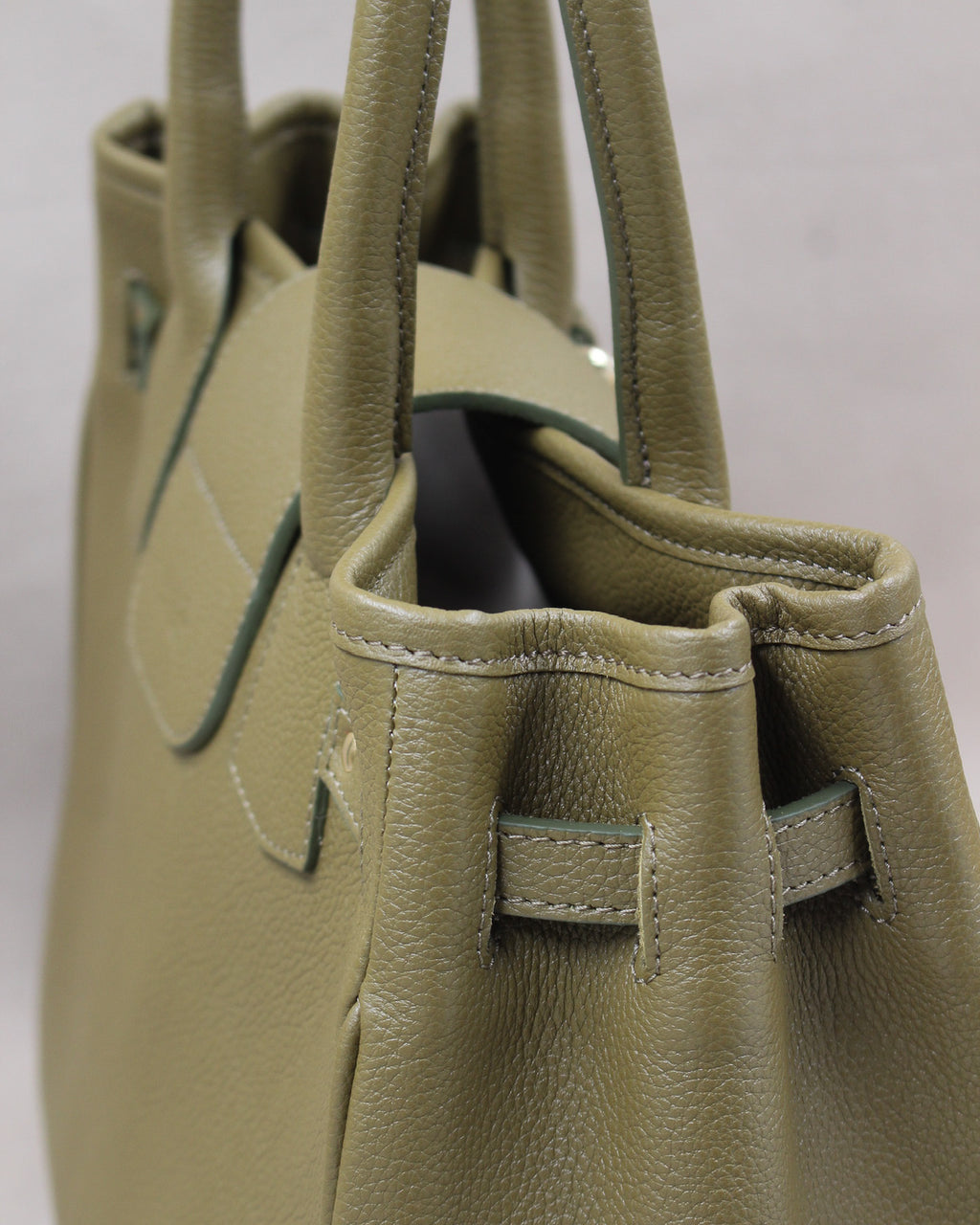 Vue de côté du sac à main Vendôme en cuir kaki grainé : soufflet, passant de sangle, anses et tranches teintées, fabrication artisanale française