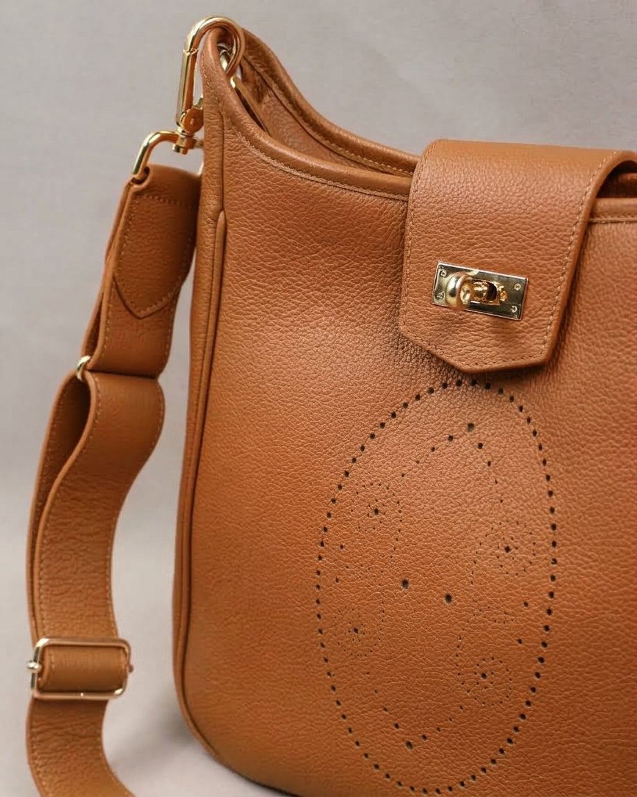Détail du sac Trianon grand format en cuir camel : motif perforé bout fleuri, fermoir tournant doré sur le rabat et large bandoulière réglable à mousqueton doré, savoir-faire artisanal français