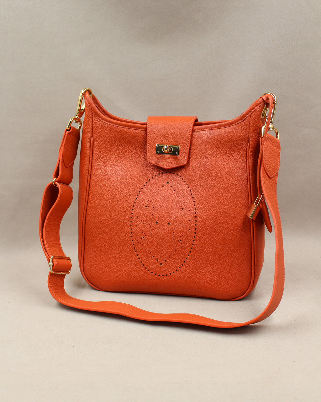 Sac Trianon grand format en cuir orange vue de trois quarts, motif perforé bout fleuri, fermoir tournant doré et large bandoulière réglable, fabriqué en France par Berthille