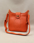 Sac Trianon grand format en cuir orange vue de trois quarts, motif perforé bout fleuri, fermoir tournant doré et large bandoulière réglable, fabriqué en France par Berthille