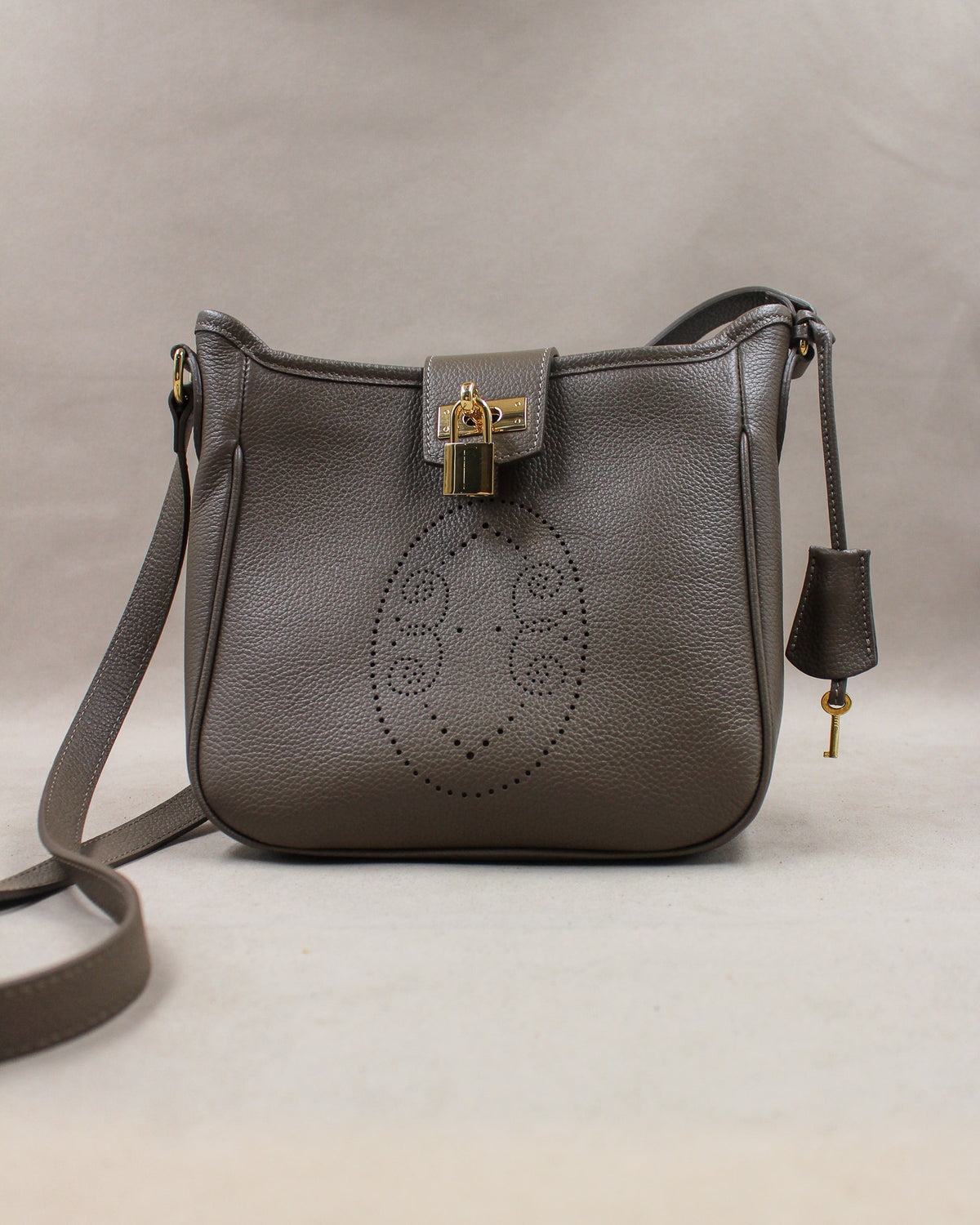 Sac Trianon en cuir gris vue de face, motif perforé bout fleuri, cadenas doré, clé et clochette en cuir, fabriqué en France par Berthille