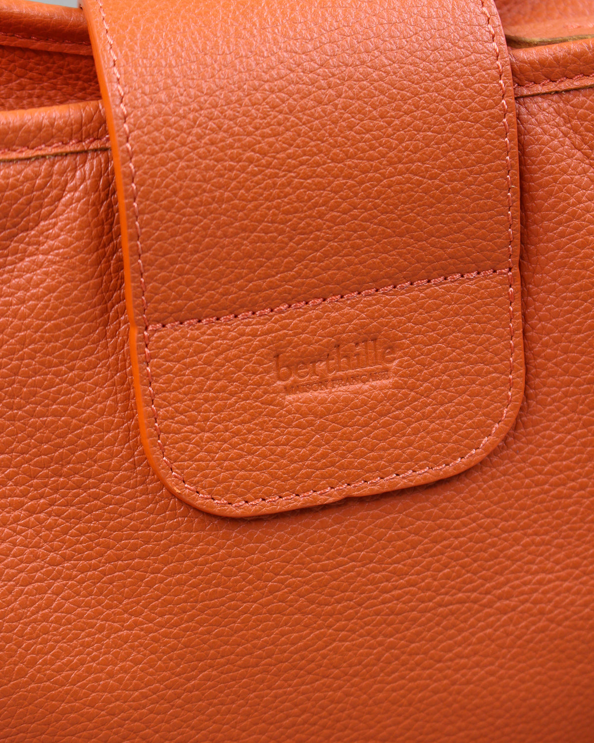 Détail du sac Trianon grand format en cuir orange grainé : logo Berthille embossé et coutures ton sur ton, maroquinerie artisanale française