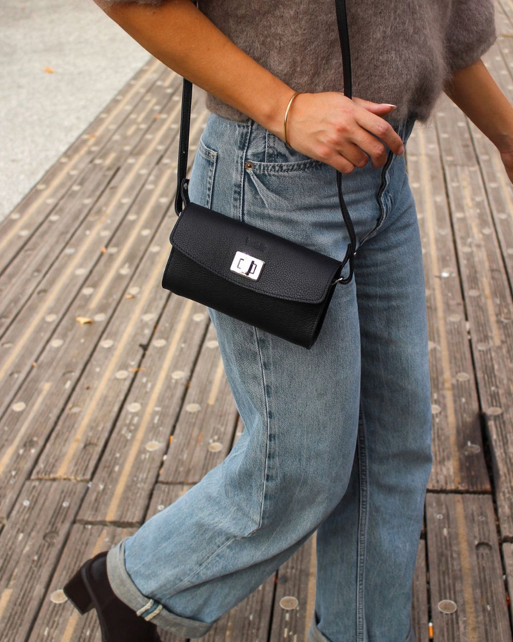 femme portant la pochette trotter berthille en coloris noir avec un jean